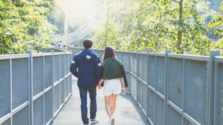 man and woman holdings hands while walking on bridge