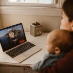 woman holding her baby while having a video call using a laptop