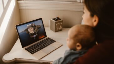 woman holding her baby while having a video call using a laptop