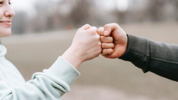 man and happy woman greeting each other with fist bump