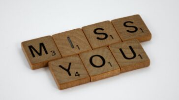 close up shot of scrabble tiles on a white surface with Miss You