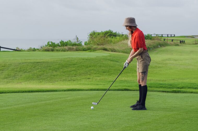a woman in red polo shirt playing golf