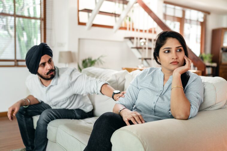 A man and a woman of Indian descent sitting on a couch
