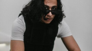 photo of Realestk dressed in grey and black putting on dark glasses